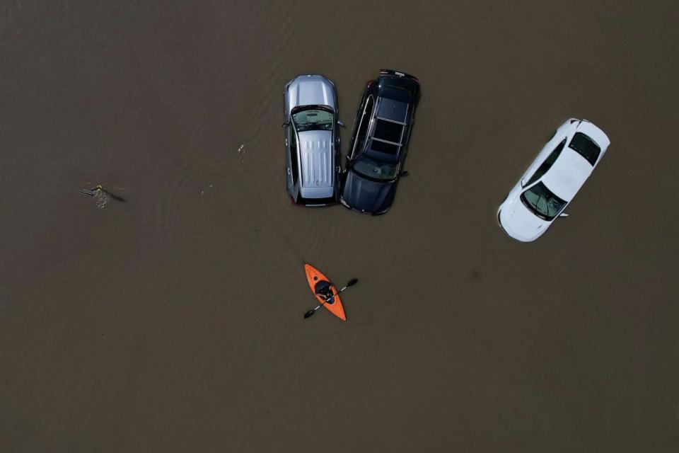 PHOTO: A person in a canoe passes parked cars partially submerged by floodwaters from recent rainstorms in Montpelier, Vermont, on July 11, 2023. (Brian Snyder/Reuters)