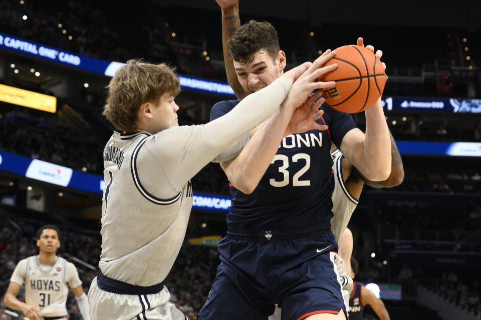 Connecticut center Donovan Clingan (32) and Georgetown guard Rowan Brumbaugh (1) battle for the ball during the first half of an NCAA college basketball game, Saturday, Feb. 10, 2024, in Washington. (AP Photo/Nick Wass)
