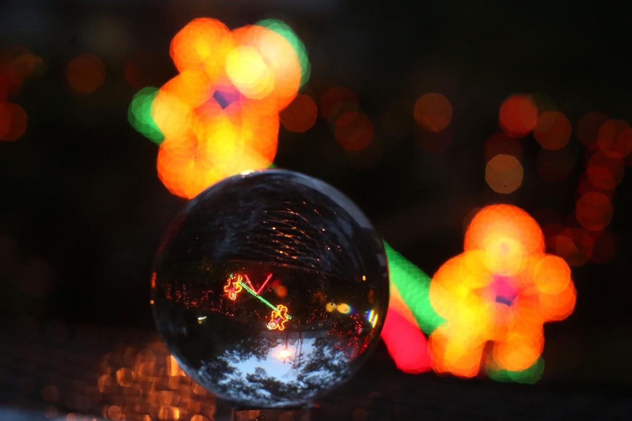 Photographed through a lens ball, a light display of gingerbread men are seen riding a see-saw at Elf Night at Dorothy B. Ovens Park, Thursday, Dec. 21, 2018. 