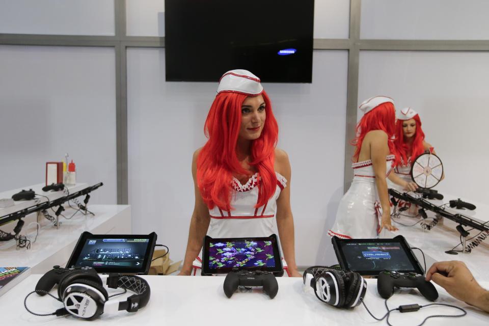 Jess Sylvia assists a show attendee at the Nyko booth, a manufacturer of accessories for tablets and game consoles, during the Electronic Entertainment Expo in Los Angeles, Tuesday, June 11, 2013. (AP Photo/Jae C. Hong)
