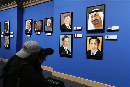 A member of the media photographs portraits of world leaders painted by former U.S. President George W. Bush at "The Art of Leadership: A President's Personal Diplomacy" exhibit at the Bush Presidential Library and Museum in Dallas, Texas April 4, 2014. REUTERS/Brandon Wade