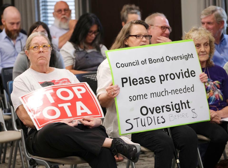 People in a crowd hold signs in September at the Council on Bond Oversight gathering to vote on whether to allow the Oklahoma Turnpike Authority to proceed with selling ACCESS Oklahoma bonds at the Oklahoma Capitol.