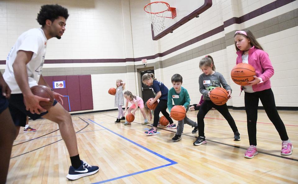 Gaston College Rhinos Joshua Johnson teaches kids the between the legs dribble during a basketball clinic held Wednesday, March 22, 2023, at First United Methodist Church on East Franklin Boulevard.