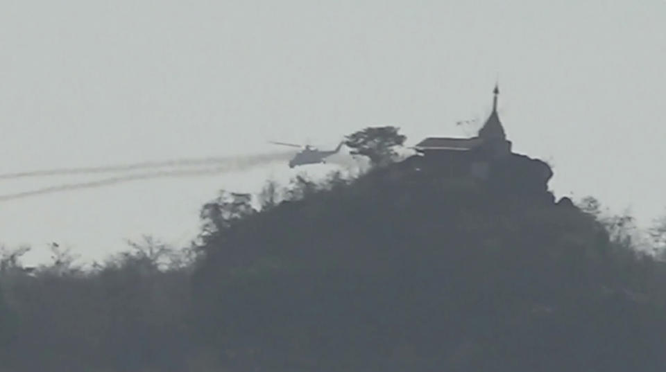 In this image taken from video provided by Free Burma Rangers, a Myanmar military helicopter fires rockets west of Loikaw in Kayah State, Myanmar on Feb. 21, 2022. While Russia’s war in Ukraine dominates global attention, Myanmar’s military is targeting civilians in air and ground attacks on a scale unmatched in the country since World War II, according to a longtime relief worker who spent almost three months in a combat zone in the Southeast Asian nation. (Free Burma Rangers via AP)