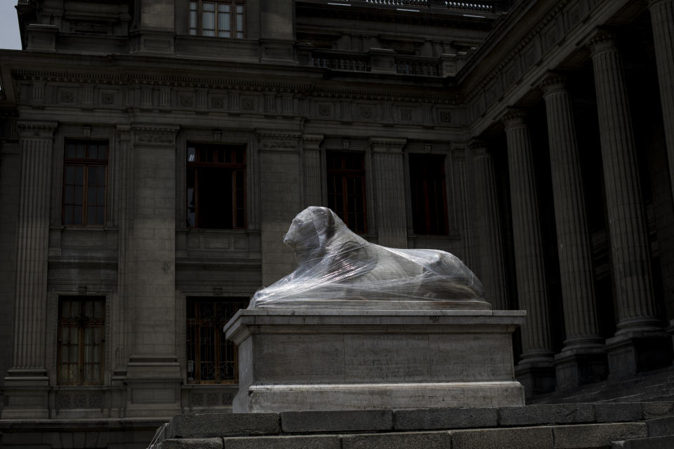 The statue of a lion that sits at the main entrance of the Palace of Justice is wrapped in plastic, in Lima, Peru, Tuesday, Dec. 1, 2020. Monuments were practically spared, in part because they were protected with plastic or fabrics, but also because they were not the aim of protesters as they filled the streets, decrying a parliamentary coup in early November when Congress voted to oust ex-President Martín Vizcarra. (AP Photo/Rodrigo Abd)