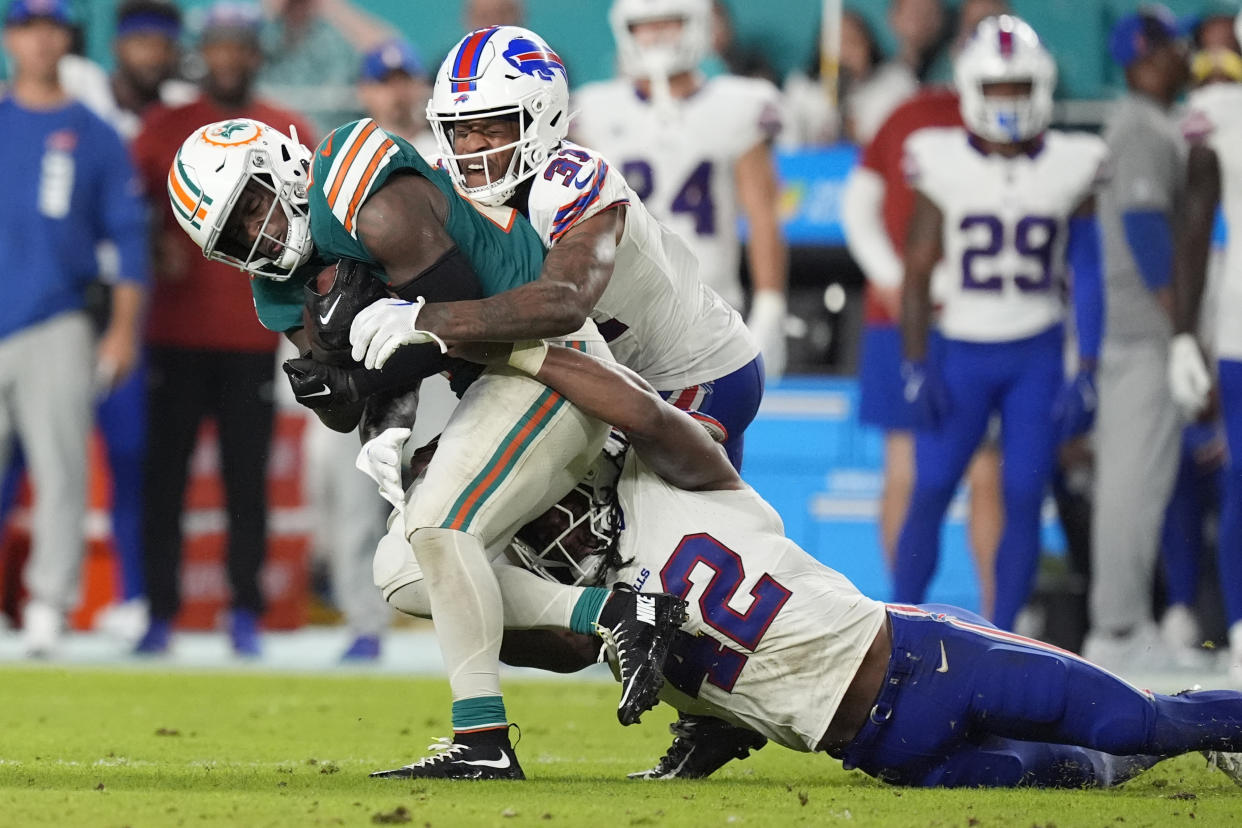 Miami Dolphins running back De'Von Achane is tackled by Buffalo Bills linebacker Dorian Williams (42) and cornerback Rasul Douglas (31) during the second half of an NFL football game, Thursday, Sept. 12, 2024, in Miami Gardens, Fla. (AP Photo/Rebecca Blackwell)