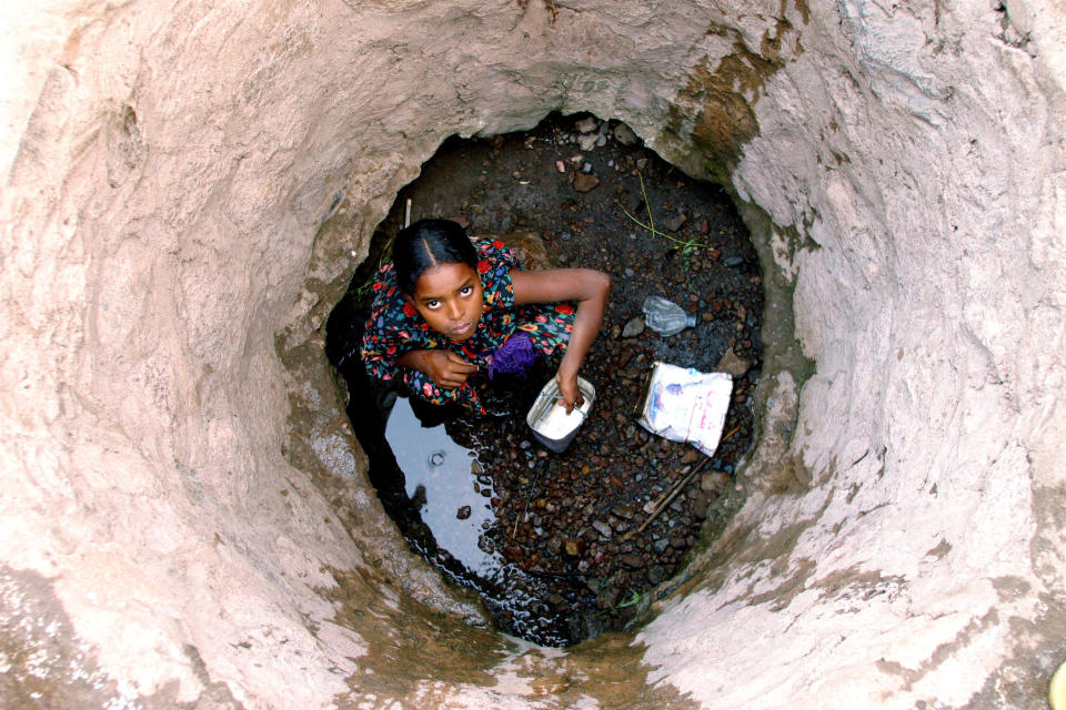 In 2003 in Djibouti, a girl collects water from the bottom of a well in a rural area in Padjourah District. Drought has depleted much of the water supply.    