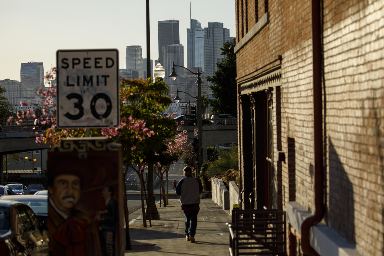 A pedestrian walks near Mariachi Plaza in Boyle Heights with the skyline of downtown Los Angeles on the horizon. (Photo: Patrick T. Fallon for Yahoo News)