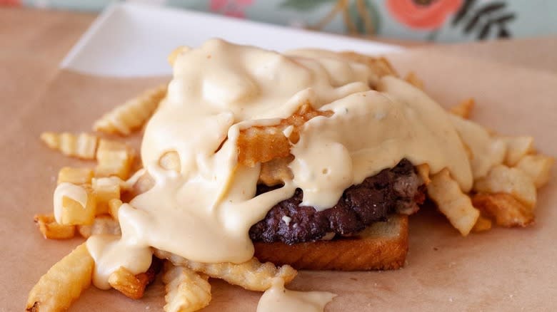 Open-faced burger with fries and cheese sauce