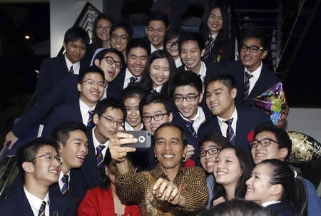 Indonesian President Joko "Jokowi" Widodo and his wife Iriana (in red) take a selfie with their son Kaesang Pangarep (holding balloon, 2nd R from top) and classmates after his graduation ceremony at Anglo-Chinese School (ACS) International in Singapore in this November 21, 2014 file photo. REUTERS/Edgar Su/Files