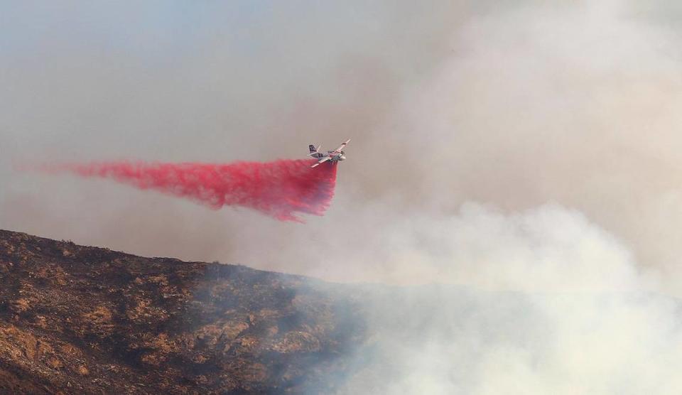 An air tanke drops retardant on a vegetation fire burning behind San Luis Obispo High School near Lizzie Street on Oct. 30, 2023.