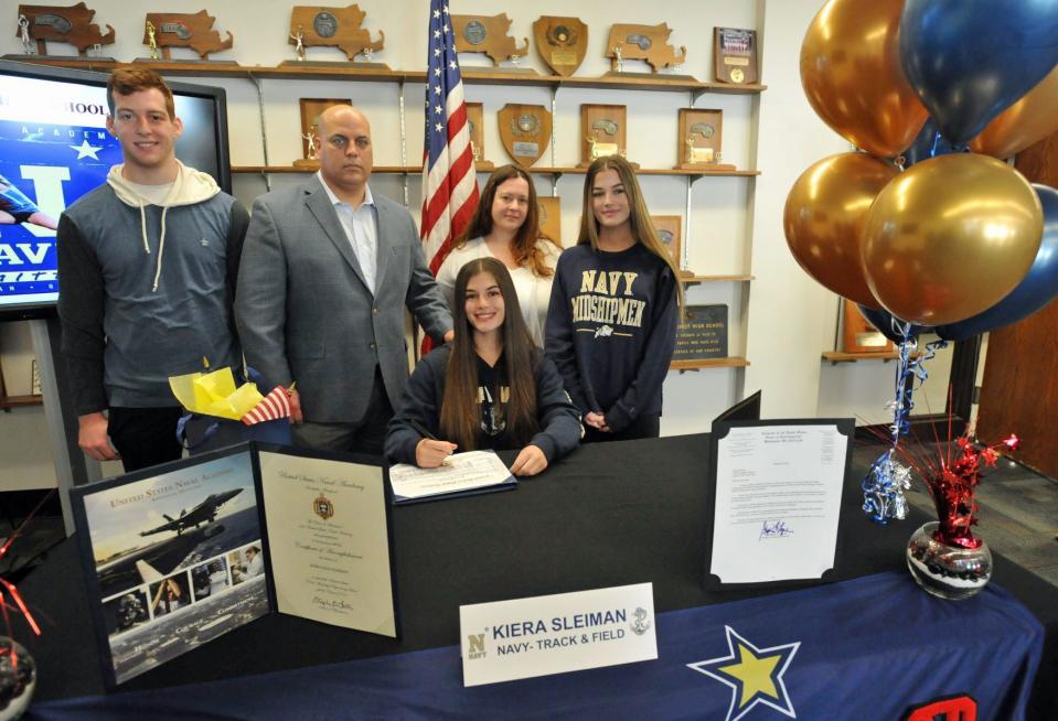 North Quincy High School senior and student-athlete Kiera Sleiman, seated, is joined by her family from left, brother, Nate, parents Ally and Leeann, and sister, Kaylee, as she signs her acceptance certificate to the United States Naval Academy during a ceremony at North Quincy High School on Friday, April 29, 2022.