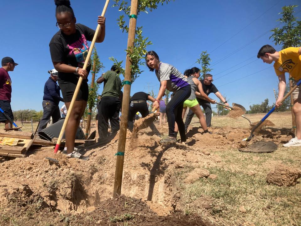 Jhoanna Echeverria, center, and Ajih Linvston, left, join Cesar Chavez High School classmates in planting trees beside Baseline Road on April 16, 2022.
