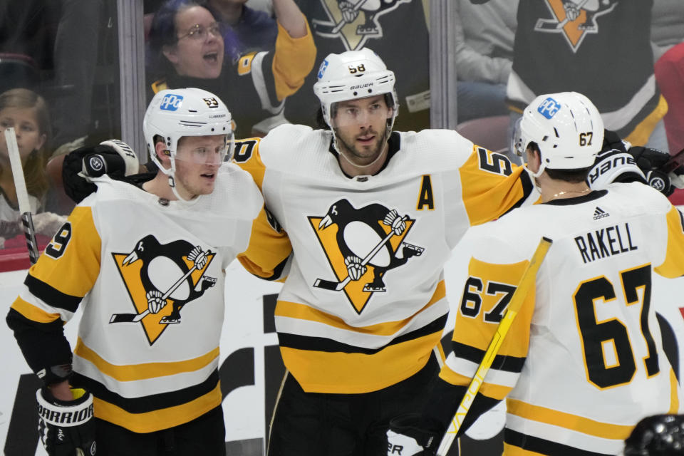 Pittsburgh Penguins defenseman Kris Letang, center, is congratulated by left wing Jake Guentzel, left, and right wing Rickard Rakell (67) after Letang scored during the second period of an NHL hockey game against the Florida Panthers, Saturday, March 4, 2023, in Sunrise, Fla. (AP Photo/Wilfredo Lee)