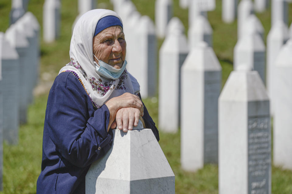 A woman leans on a grave stone in Potocari, near Srebrenica, Bosnia, Saturday, July 11, 2020. Mourners converged on the eastern Bosnian town of Srebrenica for the 25th anniversary of the country's worst carnage during the 1992-95 war and the only crime in Europe since World War II that has been declared a genocide. (AP Photo/Kemal Softic)