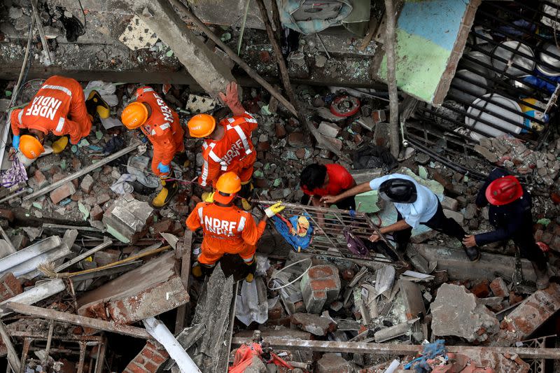 National Disaster Response Force (NDRF) officials and firemen remove debris as they look for survivors after a three-storey residential building collapsed in Bhiwandi on the outskirts of Mumbai, India