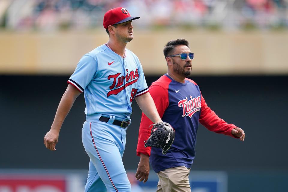 Minnesota Twins starting pitcher Tyler Mahle, left, exits the game with head athletic trainer Michael Salazar during the third inning of a baseball game against the Kansas City Royals Wednesday, Aug. 17, 2022, in Minneapolis. (AP Photo/Abbie Parr)