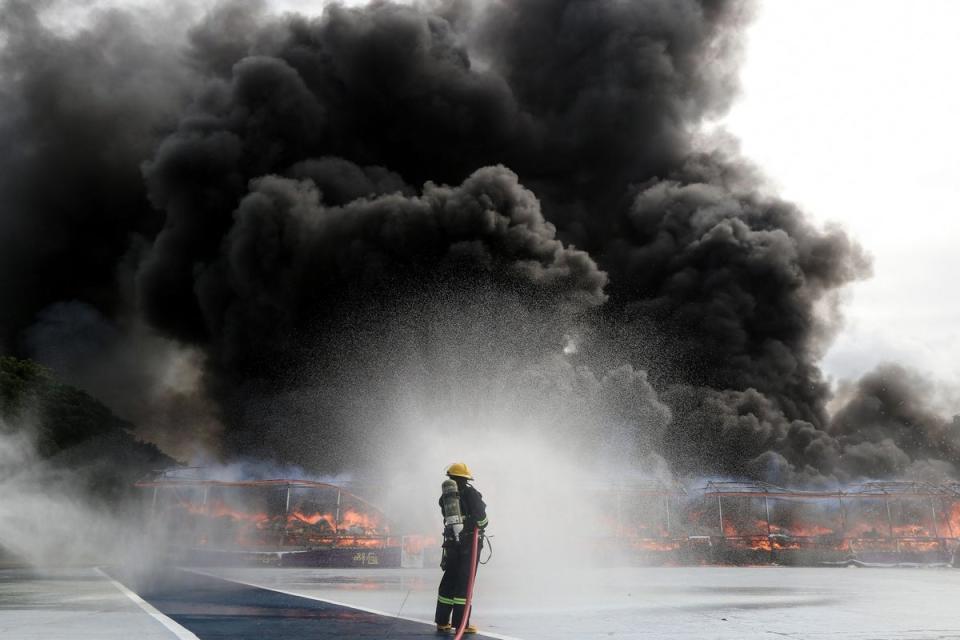 <p>A firefighter sprays water to control the burning of seized illegal drugs during a destruction ceremony in Yangon </p> (AFP via Getty Images)