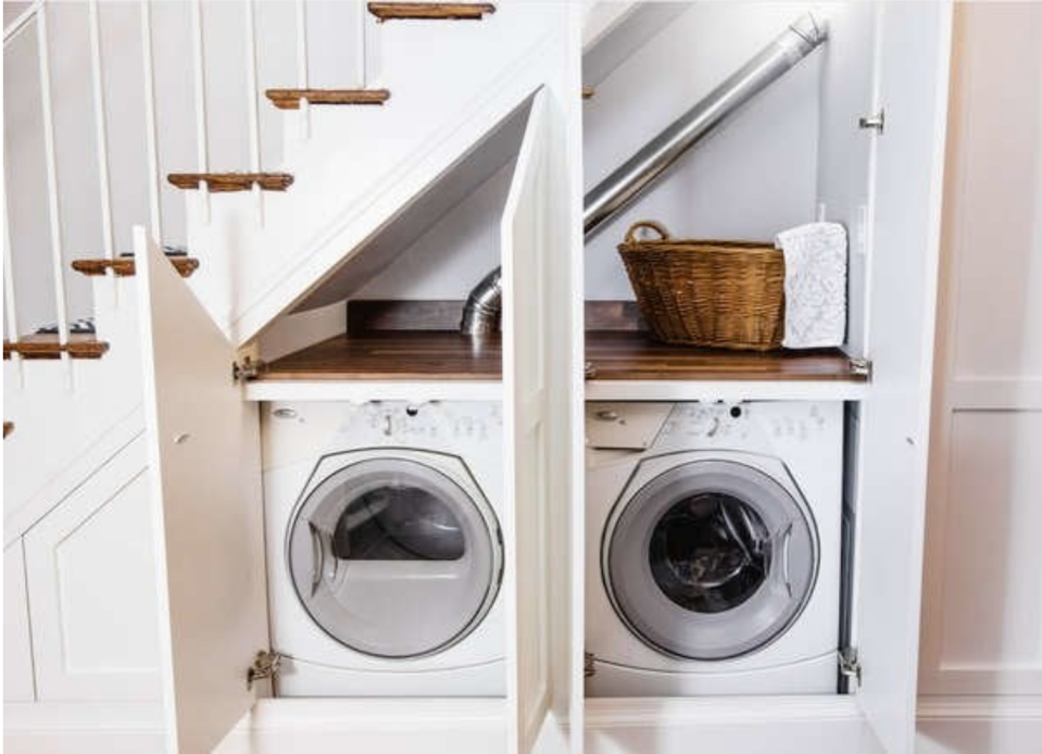 a washer and dryer hidden beneath a staircase in a nook with two open doors 