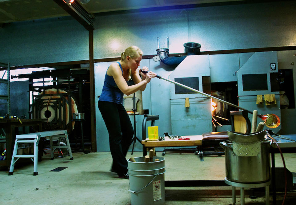 In this undated photo provided by April Wagner, Wagner works with a blow torch and hot glass in her Detroit, Mich., studio. (Sebastian Sullen/April Wagner via AP)