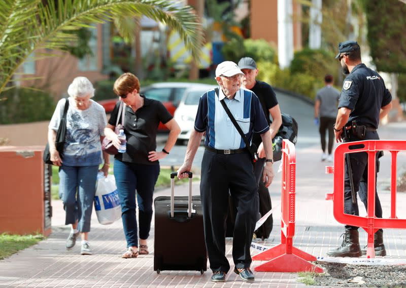 Tourists leave the hotel H10 Costa Adeje Palace, which is on lockdown after novel coronavirus has been confirmed in Adeje