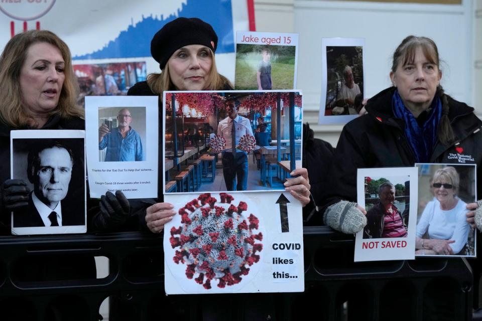 COVID campaigners and families of those who died during the pandemic hold placards and photographs of loved ones (AP)