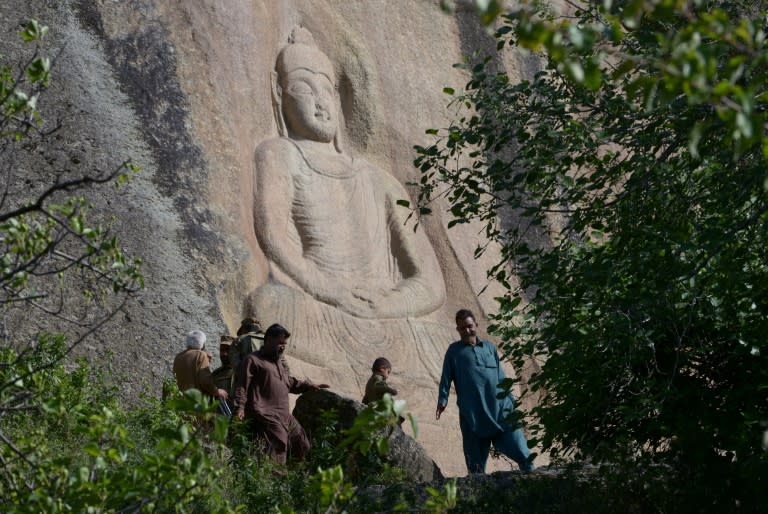 Vistors walk past the Buddha of Swat, a seventh-century sculpture carved into a mountain in the northwestern Swat Valley of Pakistan