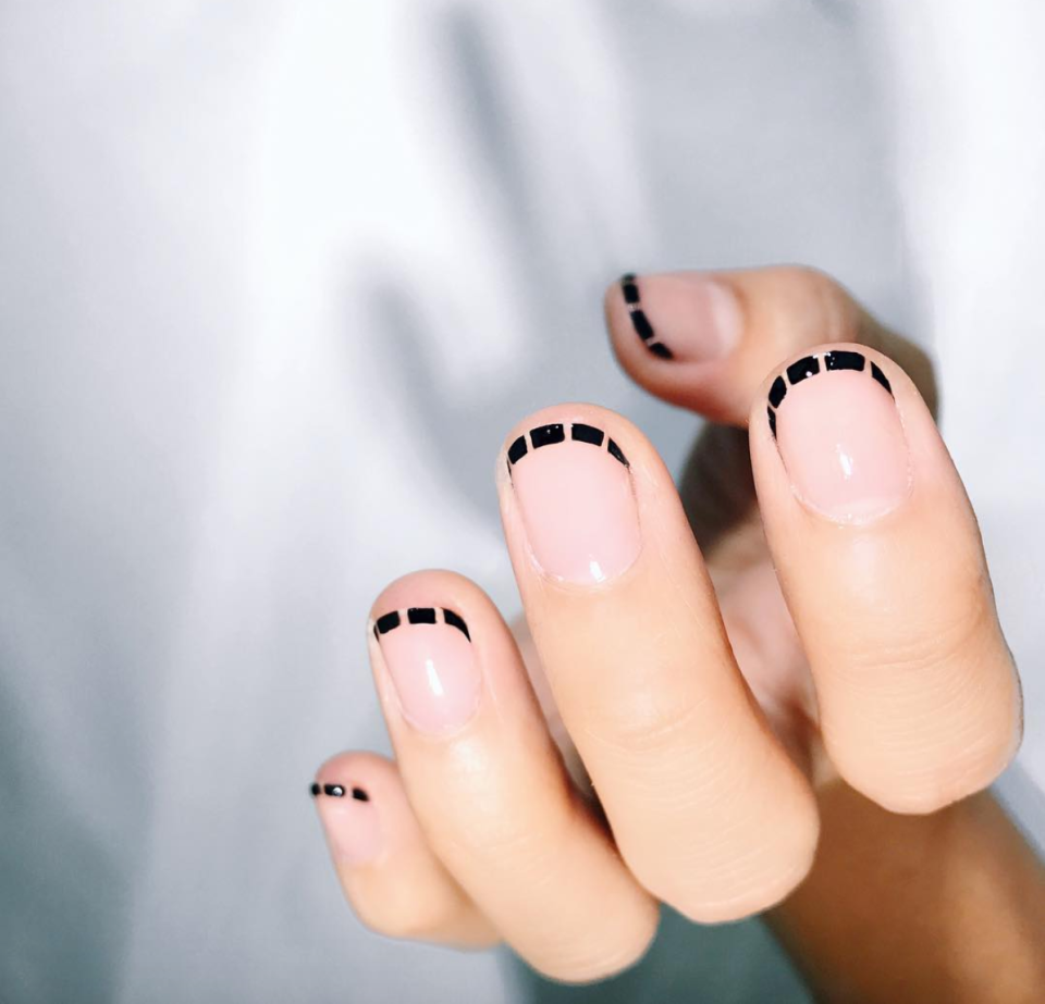 If you're looking for a more minimalist version of stitched tips, here it is. Just trace a line of black along the edge of your nail, dip a toothpick into remover, and use it to create tiny cutouts.