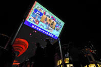 People wearing face masks to help curb the spread of the coronavirus walk by a giant TV screen broadcasting news of U.S. President Donald Trump, center, and other leaders participating in a virtual G20 summit, at a shopping mall in Beijing, Sunday, Nov. 22, 2020. The Group of 20 summit opened on Saturday with appeals by the world's most powerful leaders to collectively chart a way forward as the coronavirus pandemic overshadows this year's gathering, transforming it from in-person meetings to a virtual gathering of speeches and declarations. (AP Photo/Andy Wong)