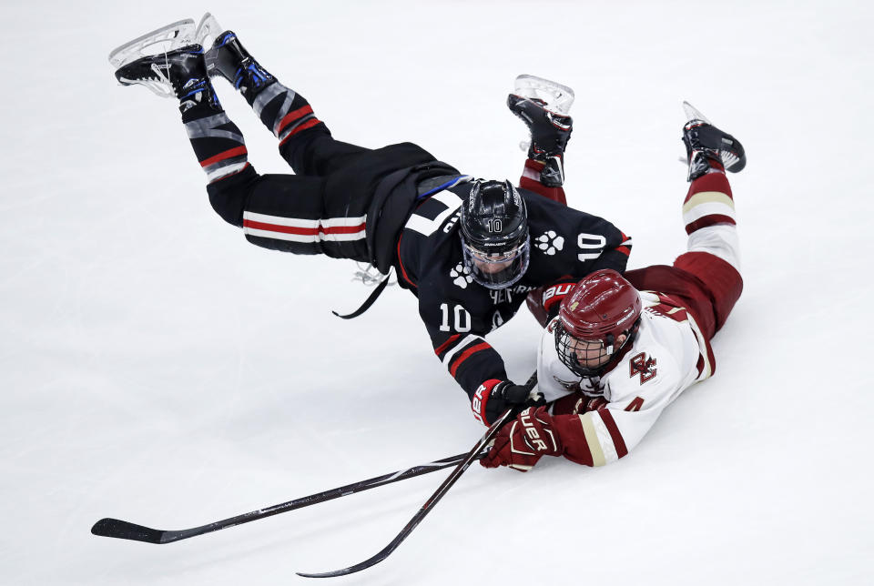 Northeastern forward Brandon Hawkins, left, and Boston College defenseman Michael Kim, right, collide as they chase the puck during the first period of the NCAA hockey Beanpot tournament championship game in Boston, Monday, Feb. 11, 2019. (AP Photo/Charles Krupa)