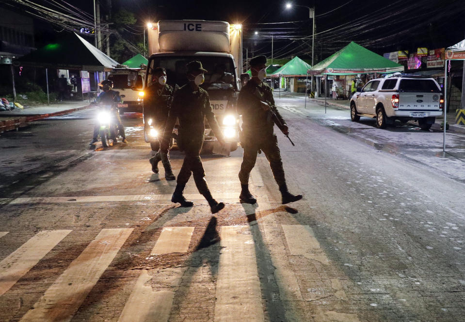 Filipino army troopers cross a road as they arrive to augment police in Valenzuela, metropolitan Manila, Philippines early Sunday March 15, 2020. Thousands of Philippine police, backed by the army and coast guard, have started sealing the densely populated capital from most domestic travelers in one of Southeast Asia's most drastic containment moves against the coronavirus. For most people, the new coronavirus causes only mild or moderate symptoms. For some, it can cause more severe illness, especially in older adults and people with existing health problems. (AP Photo/Aaron Favila)