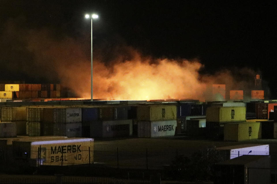 In this photo released by the Syrian official news agency SANA, shows flames rising from the scene of a missile attack, at the seaport of the coastal city of Latakia, Syria, Tuesday, Dec. 7, 2021. Syria’s military said Israeli warplanes fired the missiles causing fire without inflicting any human losses. Syria’s state media quoted an unnamed military official as saying that several missiles struck the containers area in the port early on Tuesday, setting some of them on fire. (SANA via AP)