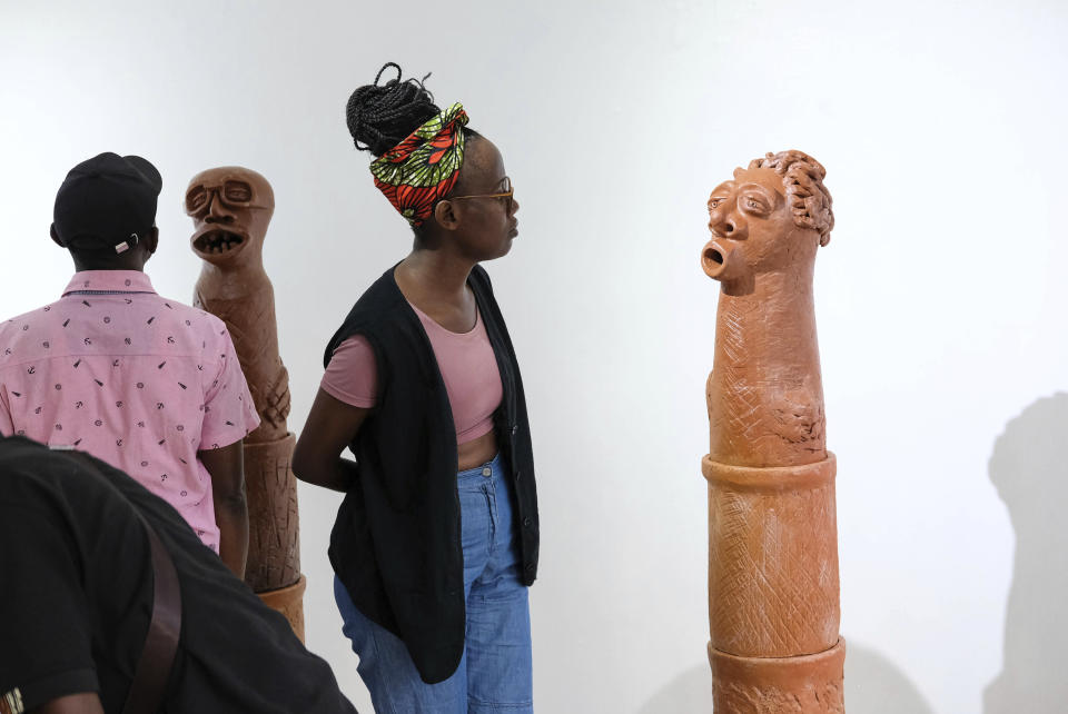 A lady looks at a sculpture piece during Lilian Nabulime's "Olugamba exhibition at Xenson Art Space in Kamwokya, Kampala, the capital of Uganda, on Tuesday Nov.28 2023. Lilian Nabulime hasn't forgotten the time in the 1990s when the Ugandan capital had just one commercial art gallery, a small space that emerging artists struggled to get into. Now there are at least six in Kampala, including one whose curators recently exhibited the sculptor's contrarian work. (AP Photo/Hajarah Nalwadda.)