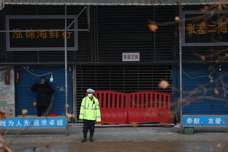A police officer wearing a mask stands in front of the closed seafood market in Wuhan