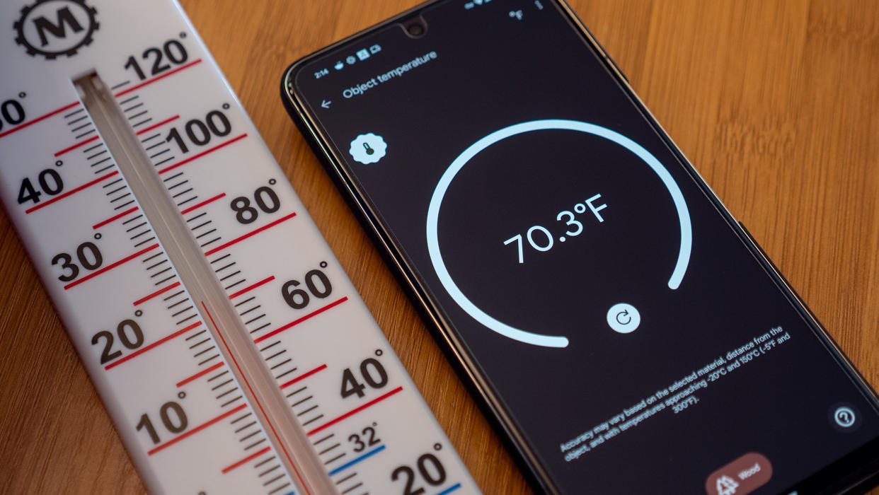  A Google Pixel 8 Pro measuring temperature next to a thermometer. 