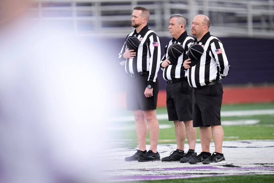 Referees hold their hats over their hearts and listen to the national anthem before a Watterson at DeSales boys lacrosse game in April.