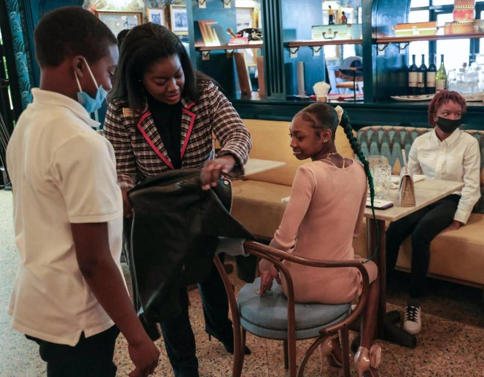 Tyquane Hankerson, 14, watches as Zakiyyah Shakir demonstrates the proper way to seat a lady at the table during a lunch etiquette demonstration at Red Rooster restaurant, the popular Overtown restaurant founded by Chef Marcus Samuelsson. From left, Tyquane, Shakir, Telrica Williams, 14, and Tacora Bryan, 16.