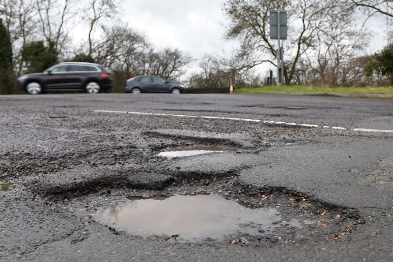 A car passes potholes on a road in the county of Cambridgeshire. British towing services are called out tens of thousands of times a month in the fight against the country's "pothole pandemic." Can the government, which plans to spend billions of pounds to tackle the problem, finally fix the issue or will a new anti-pothole robot beat them to it? Joe Giddens/Press Association/PA Archive/dpa