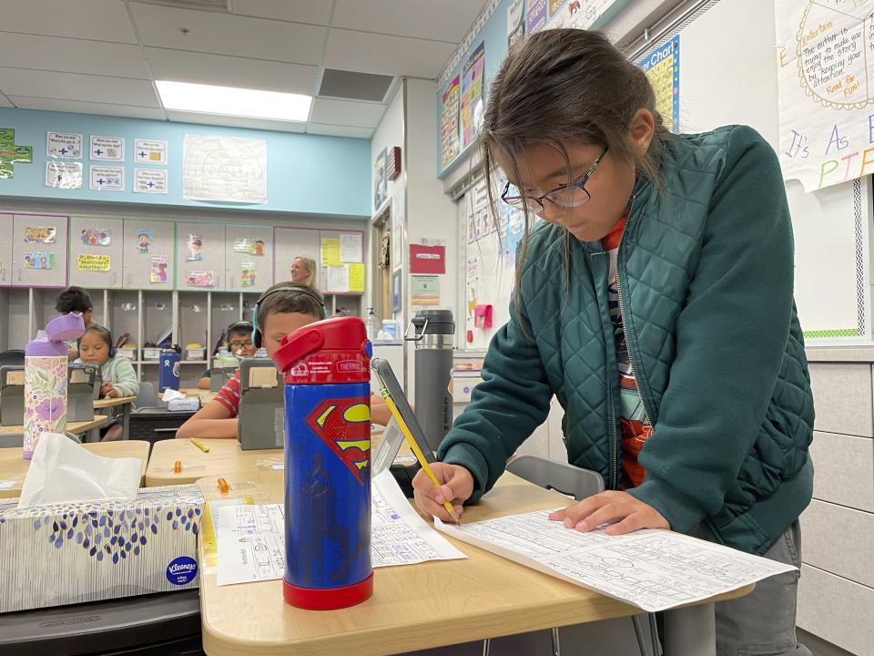 This Sept. 21, 2022 image shows a second-grade student filling out a worksheet at Judy Nelson Elementary School in Kirkland, New Mexico. The closure of the nearby San Juan Generation Station and the adjacent mine is resulting in the loss of hundreds of jobs and tax revenue for a local school district that serves primarily Native American students. (AP Photo/Susan Montoya Bryan)