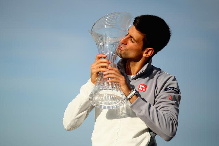 Novak Djokovic of Serbia holds the winners trophy on the beach after defeating Rafael Nadal of Spain on March 30, 2014 in Key Biscayne, Florida