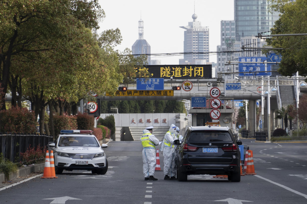 Traffic police wearing protective suits check on a vehicle before an underpass tunnel which has closed following the coronavirus outbreak in Shanghai. (Chinatopix via AP)