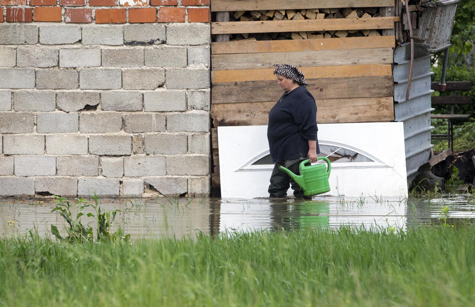 A woman walks through her flooded backyard in Sanski Most, Bosnia-Herzegovina, Tuesday, May 14, 2019. Homes and roads have been flooded in parts of Bosnia after rivers broke their banks following heavy rains, triggering concerns Tuesday of a repeat of floods five years ago when dozens died. (AP Photo/Darko Bandic)