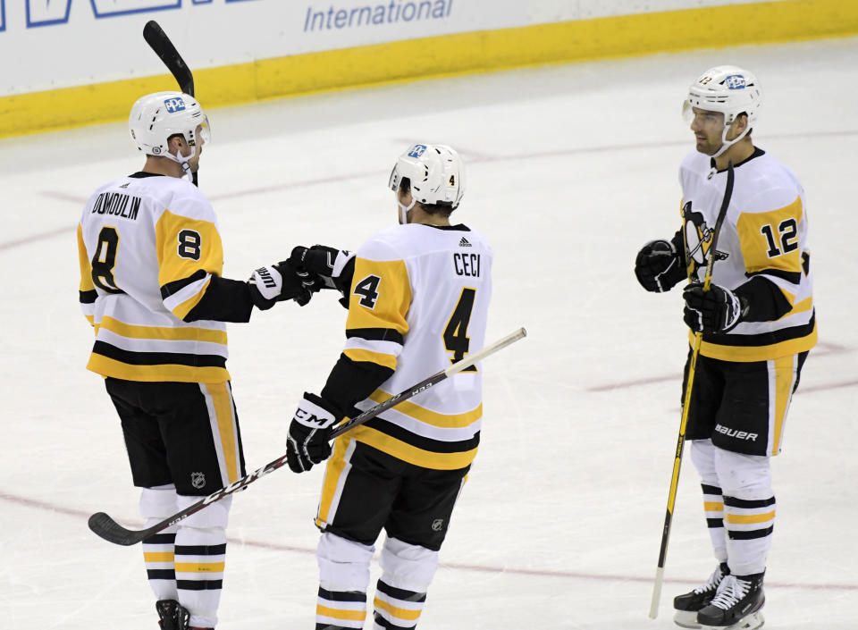 Pittsburgh Penguins defenseman Brian Dumoulin (8) celebrates his goal with defenseman Cody Ceci (4) and center Zach Aston-Reese (12) during the first period of the team's NHL hockey game against the New Jersey Devils on Friday, April 9, 2021, in Newark, N.J. (AP Photo/Bill Kostroun)