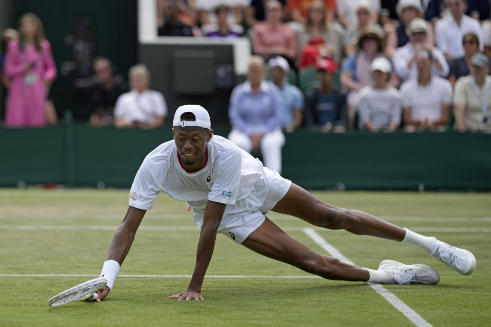 Christopher Eubanks of the US falls after playing a return to Stefanos Tsitsipas of Greece in a men's singles match on day eight of the Wimbledon tennis championships in London, Monday, July 10, 2023. (AP Photo/Alastair Grant)
