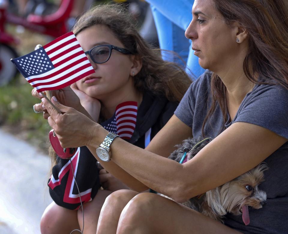 Katia, 11, left, and mother, Cindy Rodriguez, 48, sits curbside watching the parade while their 3 year-old Yorkshire Terrier, "Pixie', tries to keep cool during the city of Miami Lakes, Fla., Veterans Day Parade as veterans, Star Wars characters, cars, cheerleaders, school bands, flags, scouts, and others all paraded in honor veterans on Sunday, Nov. 10, 2019.  (Photo: Carl Juste/Miami Herald via AP)