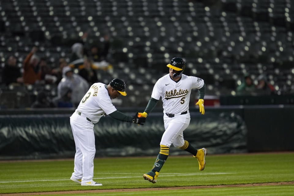 Oakland Athletics' J.D. Davis, right, celebrates with third base coach Eric Martins after hitting a solo home run against Cleveland Guardians pitcher Logan Allen during the fourth inning of a baseball game Friday, March 29, 2024, in Oakland, Calif. (AP Photo/Godofredo A. Vásquez)