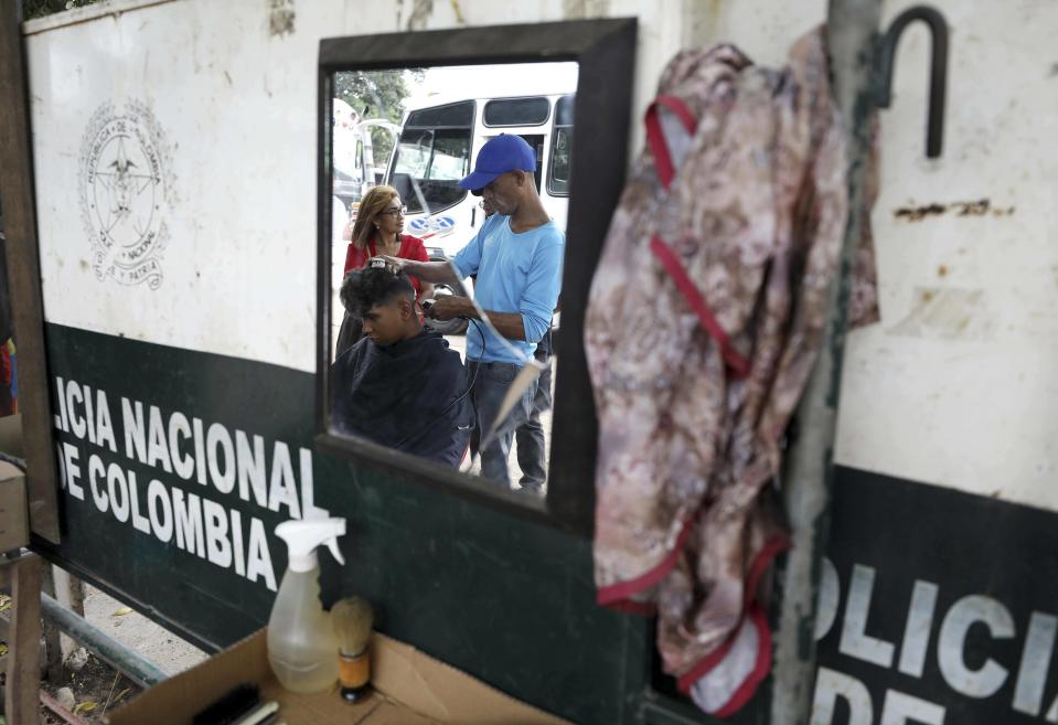 Carlos Herrera cuts the hair of a migrant, right next to the Simon Bolivar International Bridge which connects Colombia with Venezuela in La Parada, near Cucuta, Colombia, on the border with Venezuela, Tuesday, Feb. 19, 2019. Herrera earns one dollar with 30 cents for each haircut. AP Photo/Fernando Vergara)