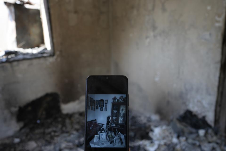 A photo on the cellphone of retiree Chrysoula Renieri depicts her living room before burned out in Loutraki, about 82 kilometres (51 miles) west of Athens, Greece, Thursday, July 20, 2023. Renieri, 72, was among dozens of people who lost their home in the area as wildfires tore through hillside scrub and forests outside Athens. (AP Photo/Thanassis Stavrakis)