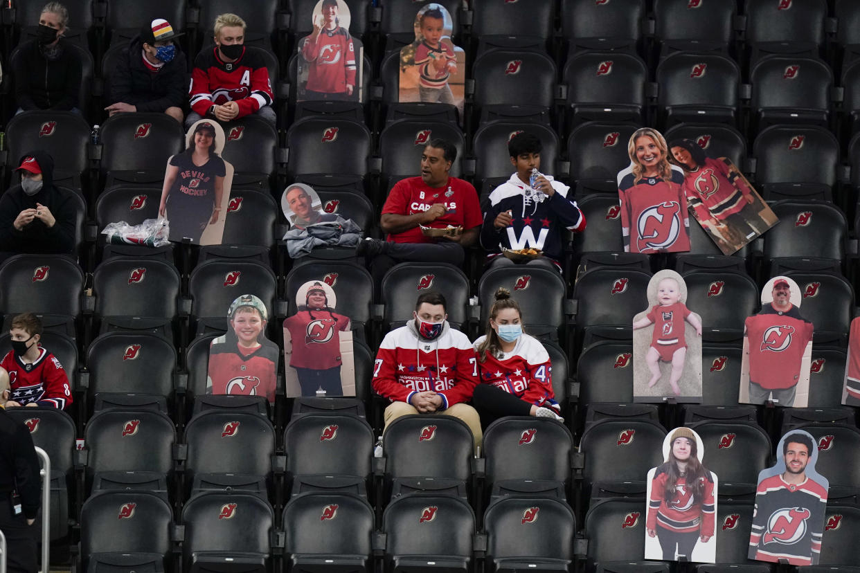 FILE - In this April 4, 2021, file photo, Washington Capitals fans sit among cutouts of New Jersey Devils fans as they watch the second period of an NHL hockey game between the Devils and the Capitals in Newark, N.J. Nearly half of new coronavirus infections nationwide are in just five states, including New Jersey — a situation that puts pressure on the federal government to consider changing how it distributes vaccines by sending more doses to hot spots. (AP Photo/Frank Franklin II)