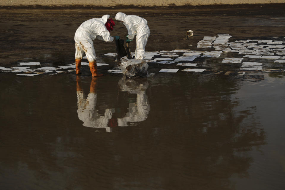 Workers carry out a clean-up operation on Mae Ramphueng Beach after a pipeline oil spill off the coast of Rayong province in eastern Thailand, Saturday, Jan. 29, 2022, At least 20 tons of oil leaked Tuesday night from an undersea hose at an offshore mooring point of the Star Petroleum Refining Co. used to load tankers, and despite efforts to disperse or contain it, some reached the beach Saturday morning, while a large slick remains at sea. (AP Photo/Nava Sangthong)